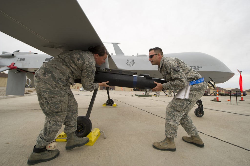 Senior Airman Bethany Lamb and Tech. Sgt. Travis Wheeler load an inert missile onto a MQ-1 Predator during a load crew competition April 5 at Holloman Air Force Base, N.M. Load crew competitions are held on a quarterly basis to help build morale through friendly competition. Lamb and Wheeler are 849th Aircraft Maintenance Squadron load crew members. (U.S. Air Force photo by Airman 1st Class Michael Shoemaker)
