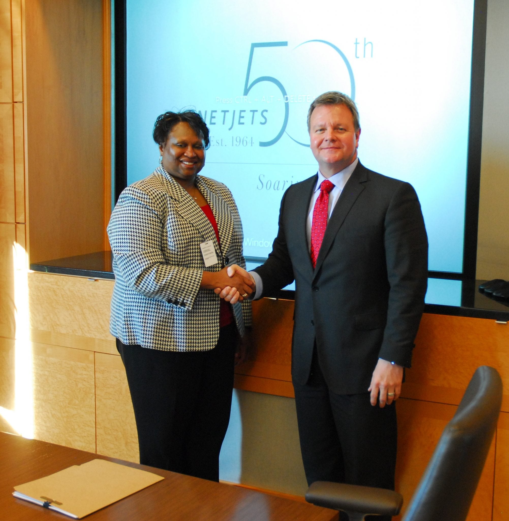 FAA Deputy Administrator for NextGen Pamela Whitley and NetJets Global Chief Operating Office and President of NetJets Aviation Bill Noe shake hands after signing new five year agreement for development and implementation of NextGen projects