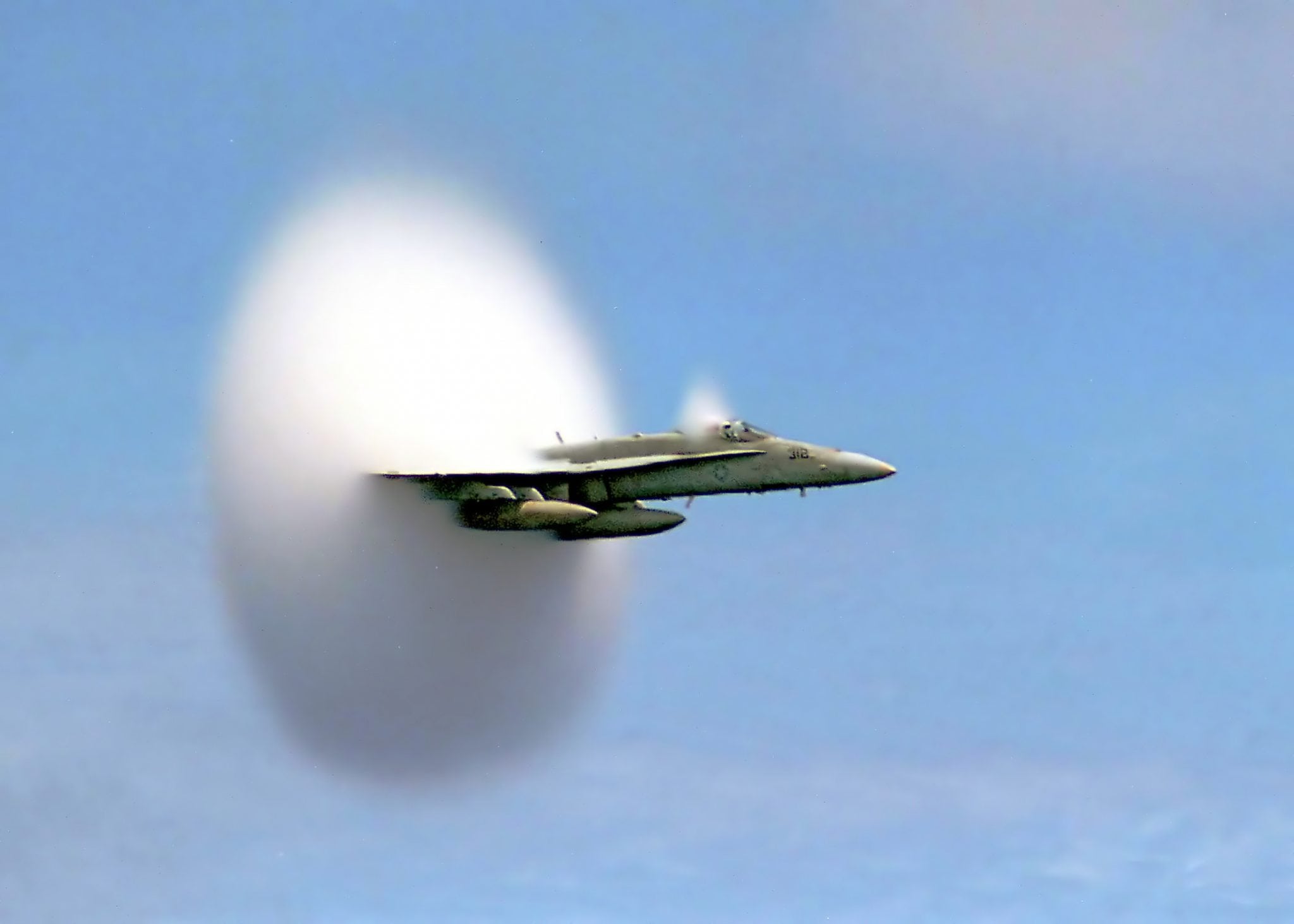 U.S. Navy F/A-18 approaching the sound barrier. The white halo is formed by condensed water droplets which result from the shock wave shedding from the aircraft.