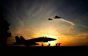 Military aircraft before take-off from aircraft carrier on sunset background